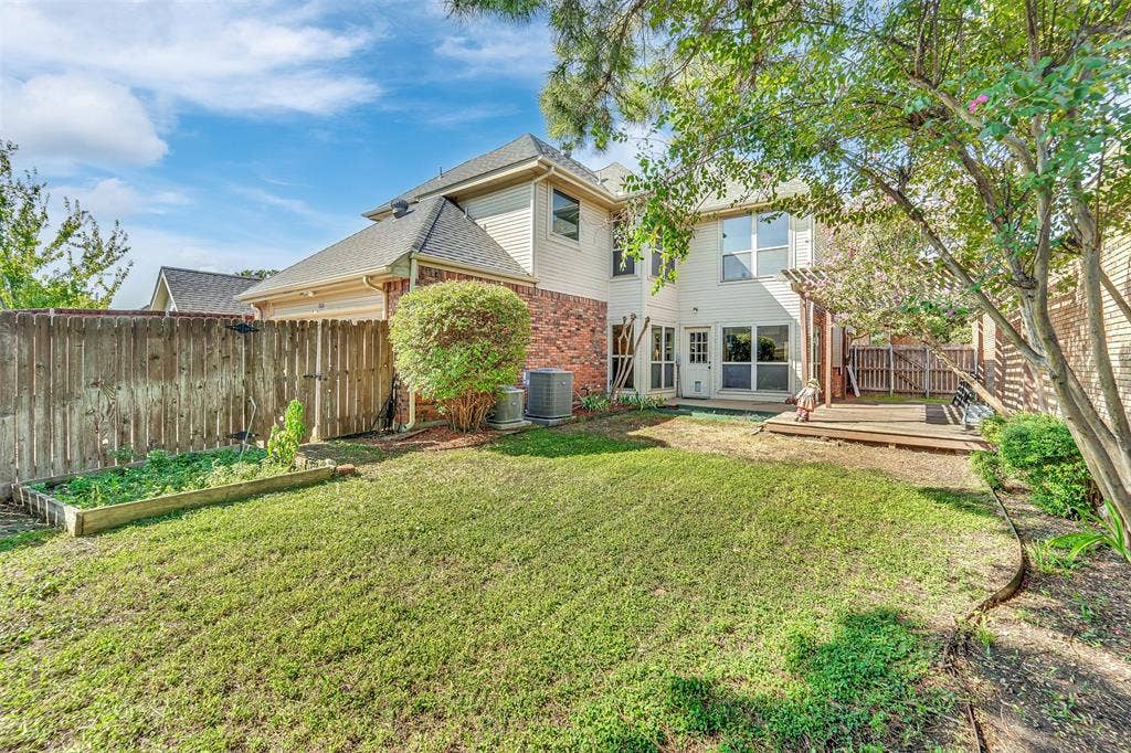 1920 Keystone Drive, Plano, TX 75075 Expansive backyard featuring a manicured lawn, raised garden bed, and a wooden deck