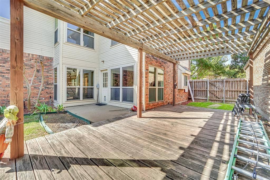 1920 Keystone Drive, Plano, TX 75075 Expansive wood deck with an overhead pergola, complemented by a concrete patio, brick exterior, and a wood privacy fence