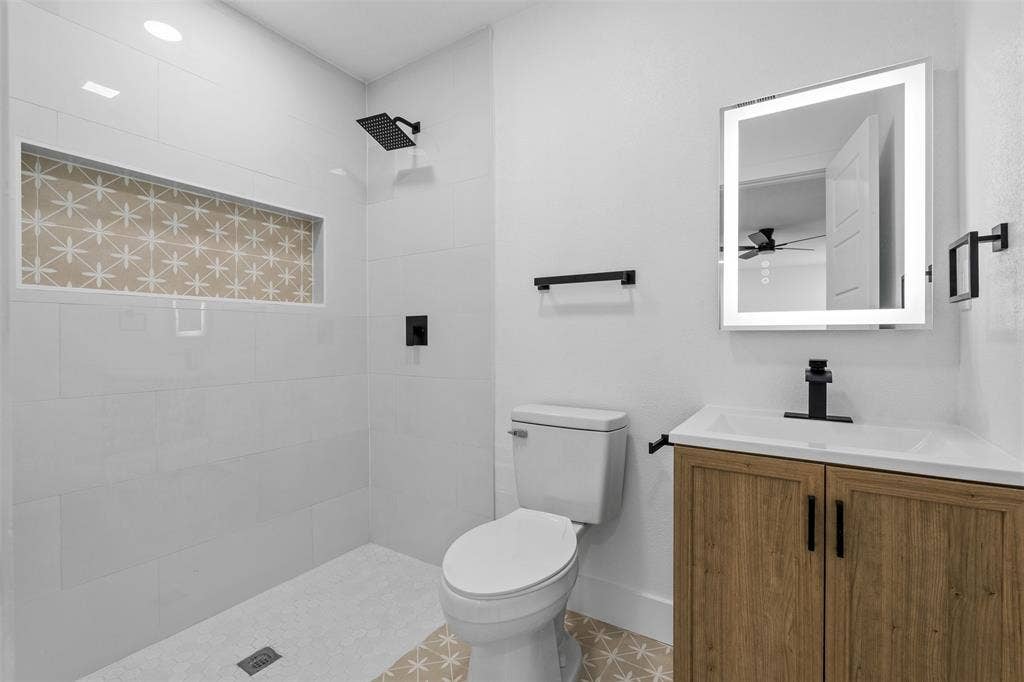 565 alcorn Avenue, Dallas, TX 75217 Walk-in shower with a decorative tiled niche, black shower fixtures, and white subway tile surround