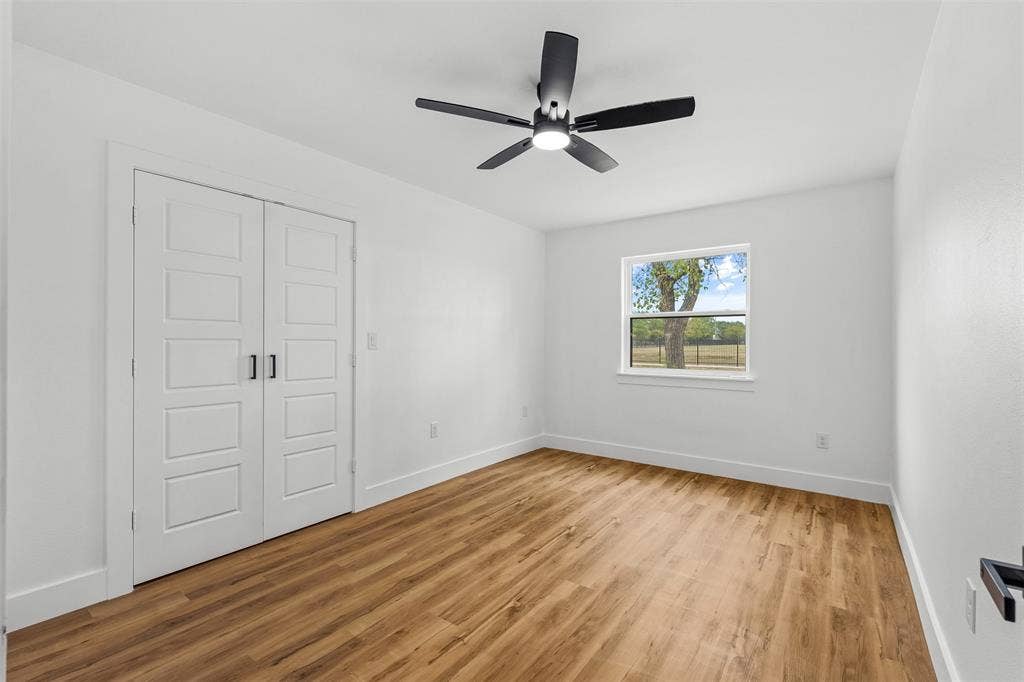 565 alcorn Avenue, Dallas, TX 75217 Wood-finish flooring, white paneled double doors, black ceiling fan with integrated lighting, and a white-framed window