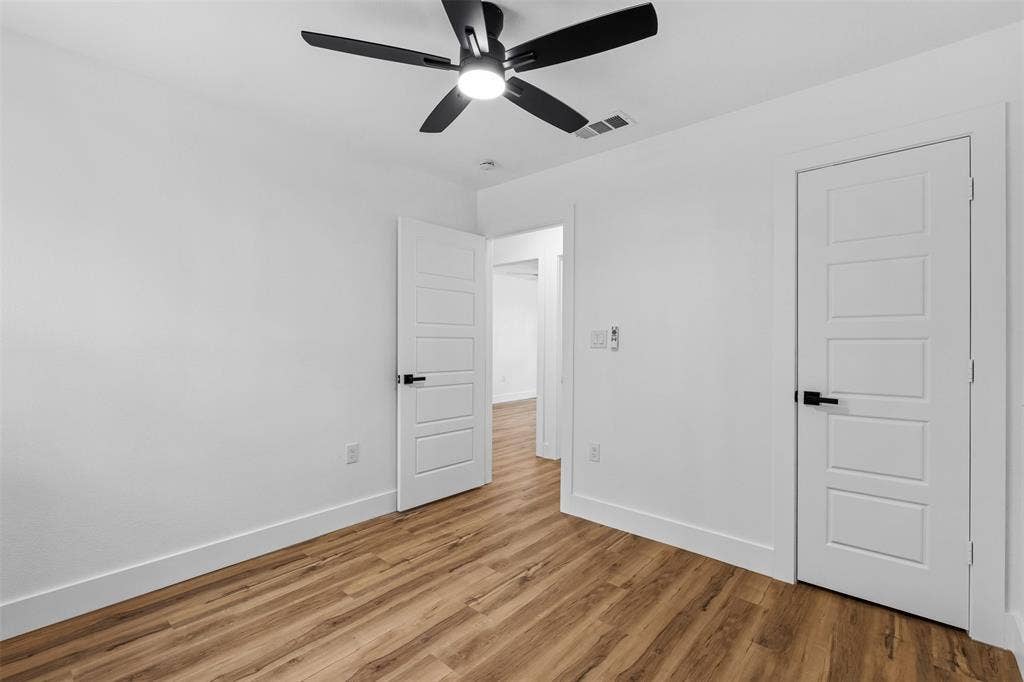 565 alcorn Avenue, Dallas, TX 75217 Wood-finish flooring, white paneled doors with black hardware, and a ceiling fan with integrated lighting