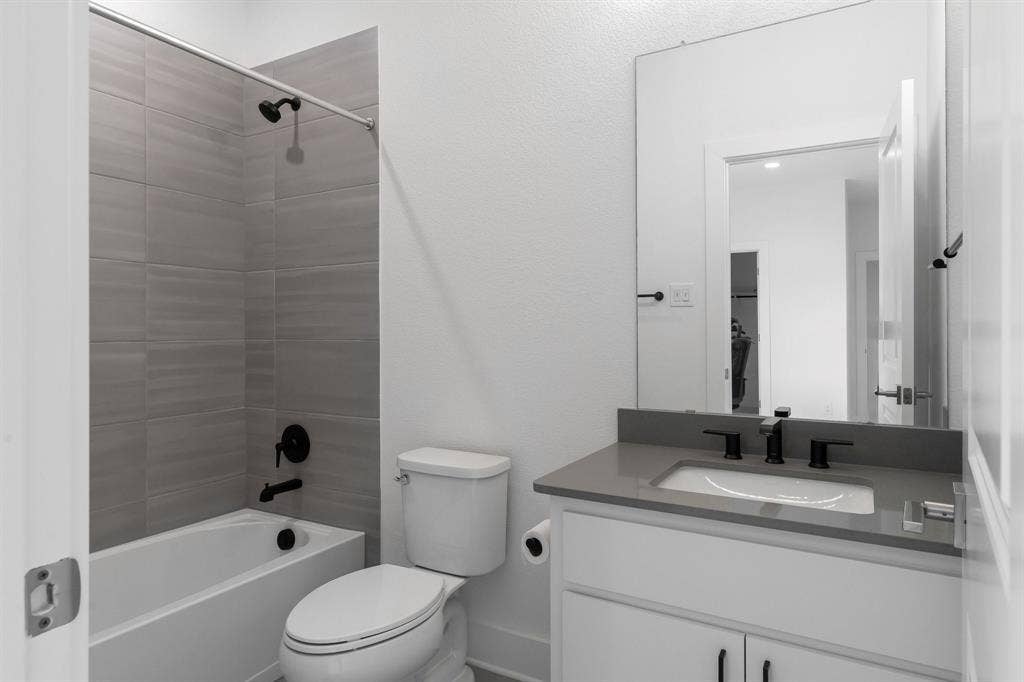 White vanity with modern black hardware, undermount sink, and light gray countertop