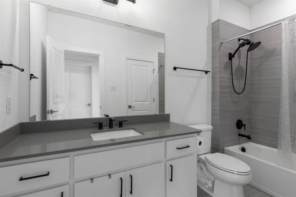 White vanity with matte black hardware, gray countertop, undermount sink, and black fixtures
