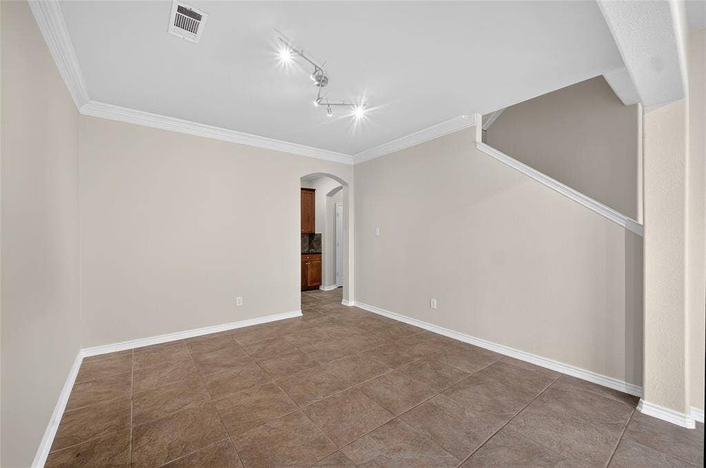 2309 Shingle Lane, Plano, TX 75074 Neutral tone wall color, crown molding, tile flooring, track lighting, arched doorway