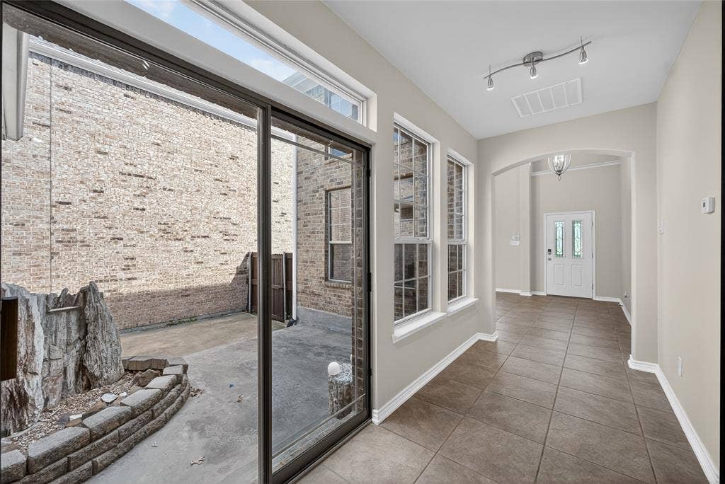 2309 Shingle Lane, Plano, TX 75074 Sliding glass door access to an outdoor patio with brick veneer walls and a rock feature