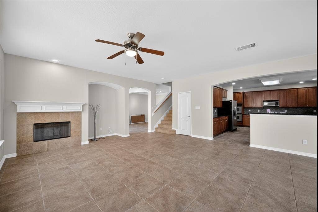 2309 Shingle Lane, Plano, TX 75074 Spacious interior featuring tile flooring, a fireplace with a white mantel, and an arched entryway
