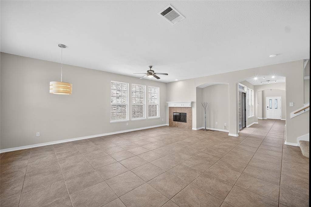 2309 Shingle Lane, Plano, TX 75074 Tile flooring throughout, white mantel fireplace, multiple windows, ceiling fan, and pendant lighting