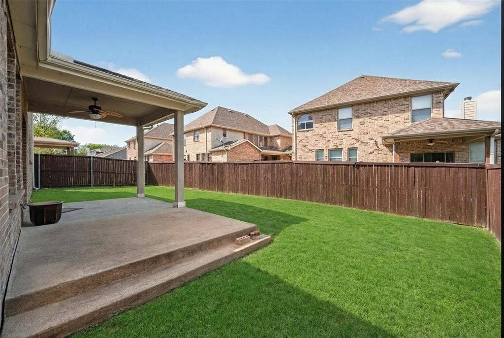 2309 Shingle Lane, Plano, TX 75074 Expansive grassy yard with a covered patio featuring a built-in ceiling fan, and a wood privacy fence
