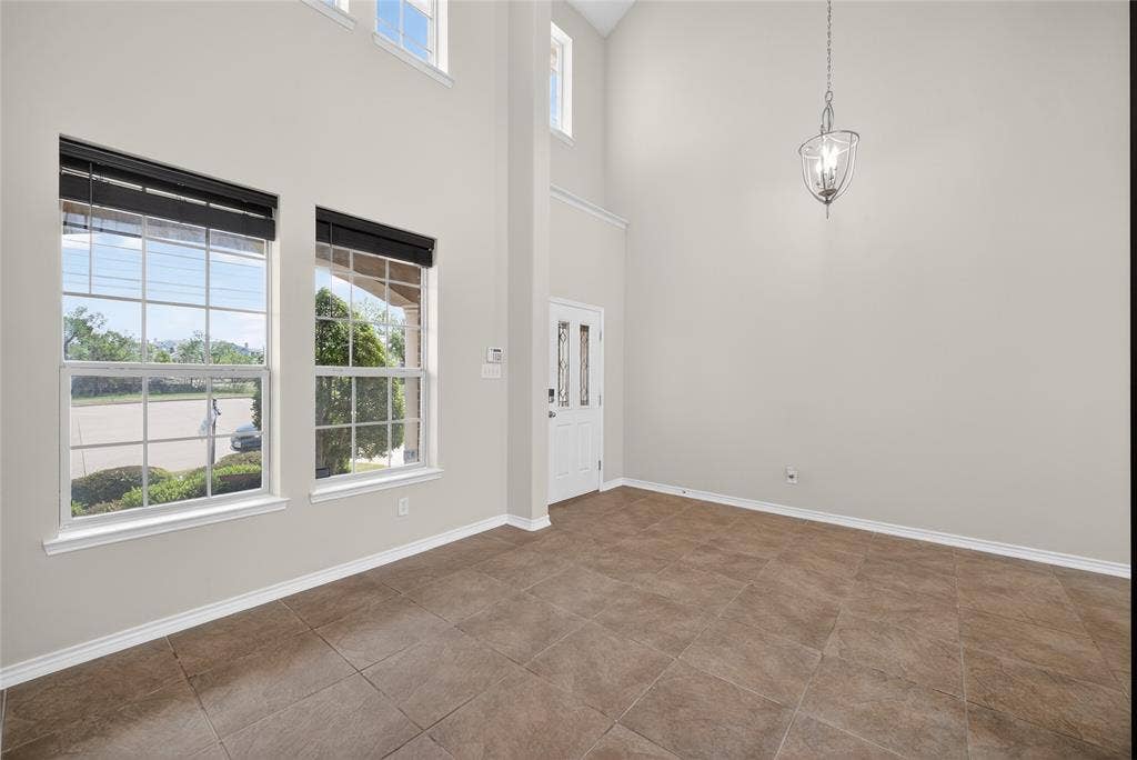 2309 Shingle Lane, Plano, TX 75074 Two-story foyer with high ceilings, large grid windows, a glass-paneled front door, and a suspended chandelier