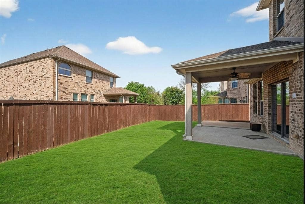 2309 Shingle Lane, Plano, TX 75074 Expansive lawn with a wood-stained privacy fence, covered patio, and ceiling fan