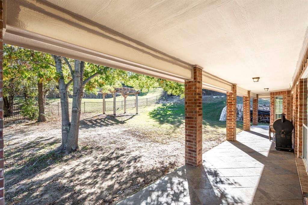 11701 Cambria Court, Fort Worth, TX 76008 Brick columned covered patio with concrete flooring, recessed lighting, and a fenced backyard