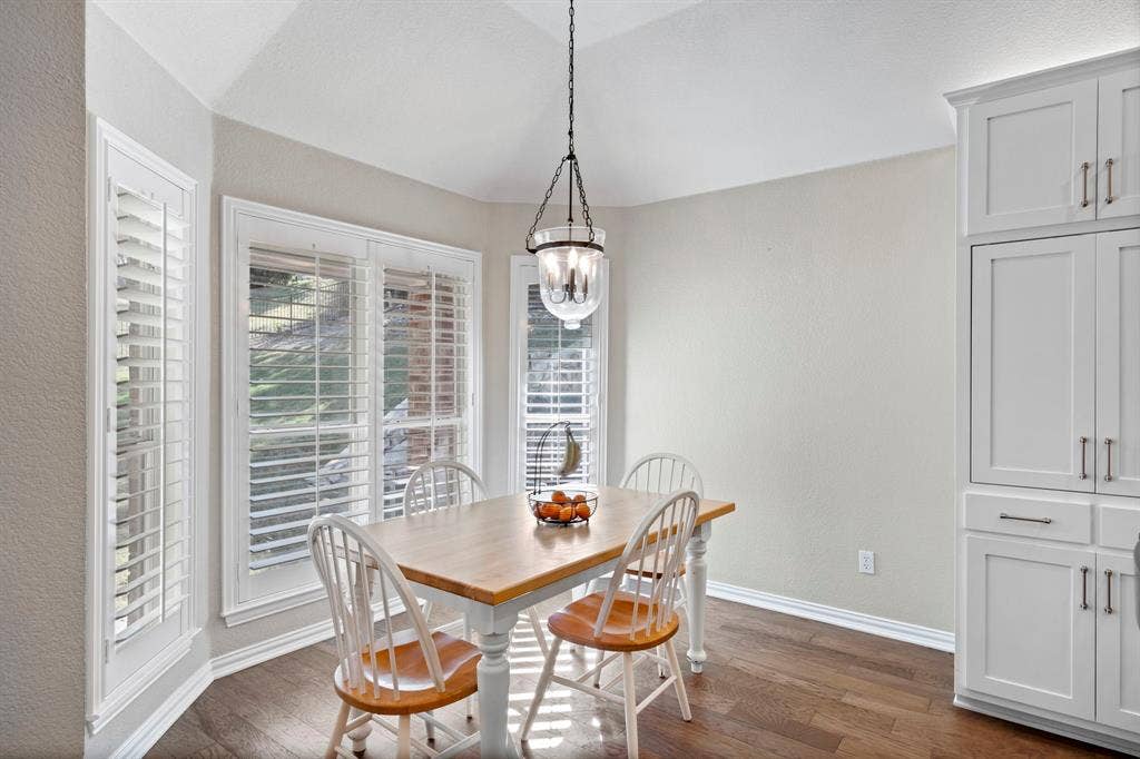 11701 Cambria Court, Fort Worth, TX 76008 Vaulted ceiling with a chandelier, wood-finish flooring, white plantation shutters, and built-in white cabinetry with silver hardware