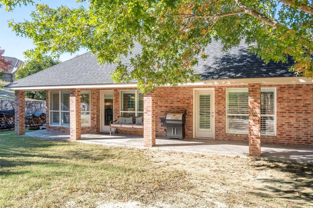 11701 Cambria Court, Fort Worth, TX 76008 Expansive brick exterior with a covered patio, multiple windows with blinds, and direct outdoor access