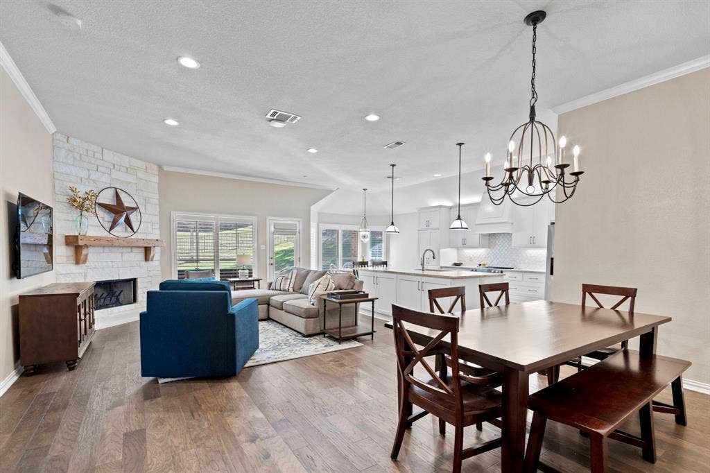 11701 Cambria Court, Fort Worth, TX 76008 Spacious living area with wood-finish flooring, a stone-accented fireplace, and a large kitchen island