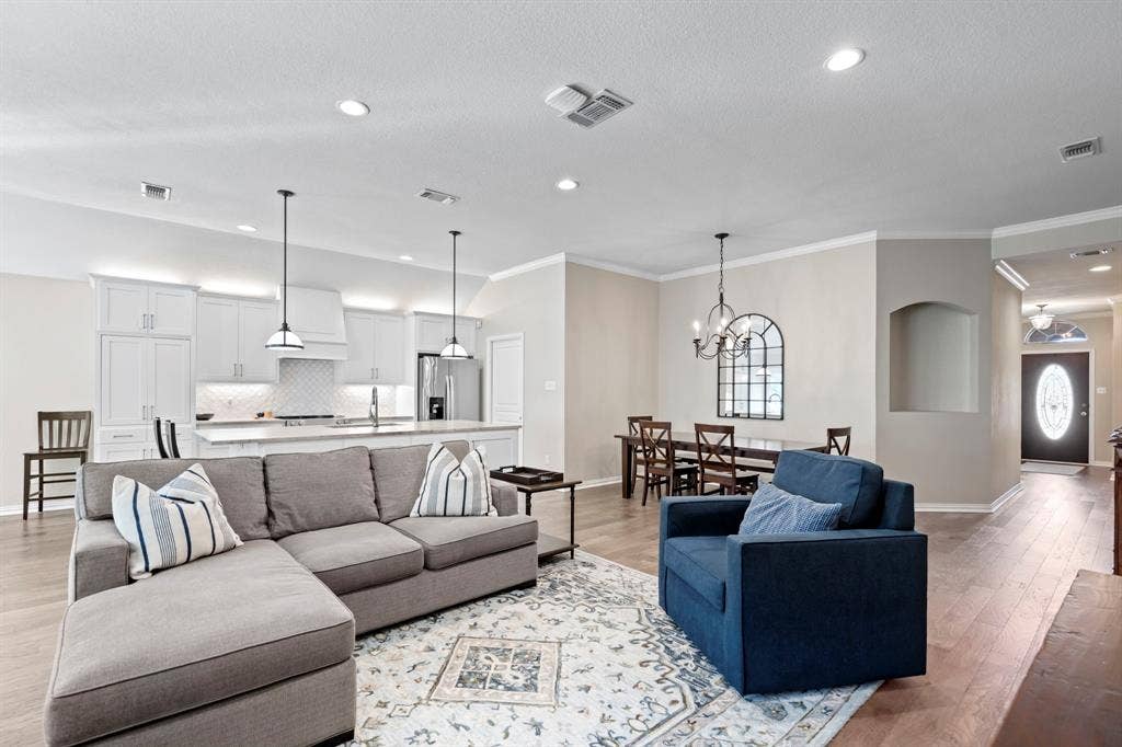 11701 Cambria Court, Fort Worth, TX 76008 Expansive open-concept living space with wood-finish flooring, recessed lighting, and crown molding