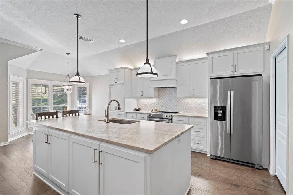 11701 Cambria Court, Fort Worth, TX 76008 Kitchen featuring a large island with sink, white shaker cabinetry, stainless steel appliances, and wood-finish flooring