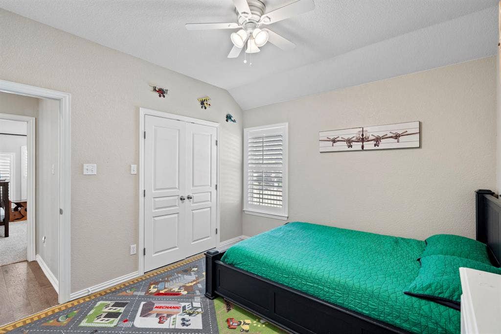 11701 Cambria Court, Fort Worth, TX 76008 Vaulted ceiling with a ceiling fan, window with plantation shutters, double closet doors, and wood-finish flooring