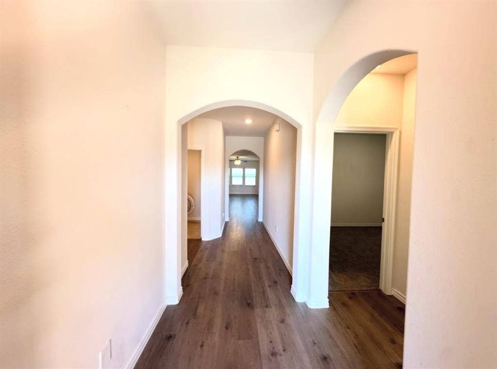 Interior hallway featuring wood-finish flooring, recessed ceiling lighting, and multiple arched entryways