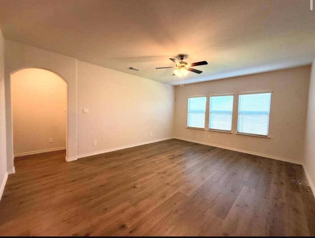 Interior space featuring wood-finish flooring, a recessed archway, and three windows