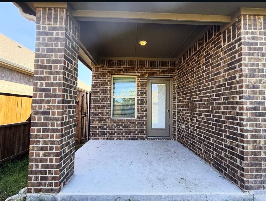 Covered brick patio featuring a concrete floor, recessed lighting, and a glass-paneled exterior door