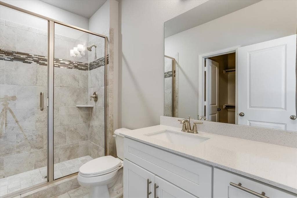 Glass-enclosed shower with tiled walls and a decorative mosaic band
