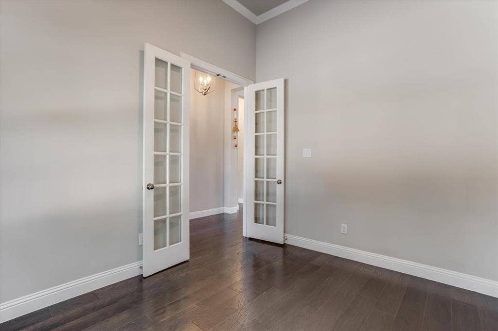 French doors with glass panels, wood-finish flooring, light gray wall tones, and crown molding