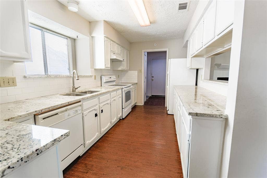 1328 Colmar Drive, Plano, TX 75023 White cabinetry, light-toned countertops, white subway tile backsplash, stainless steel double basin sink, and wood-finish flooring