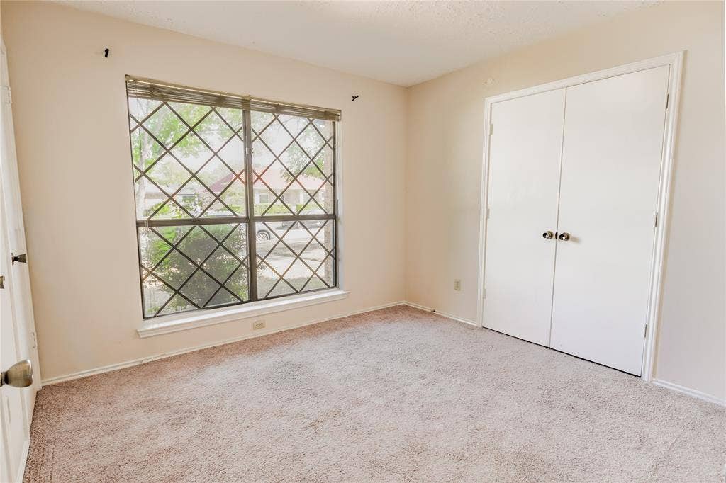 1328 Colmar Drive, Plano, TX 75023 Carpeted flooring with painted walls, a window featuring security bars, and a bi-fold closet door