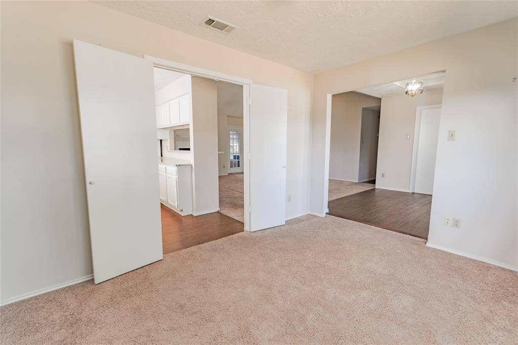 1328 Colmar Drive, Plano, TX 75023 Carpeted flooring, white bi-fold doors, archway, and wood-finish flooring
