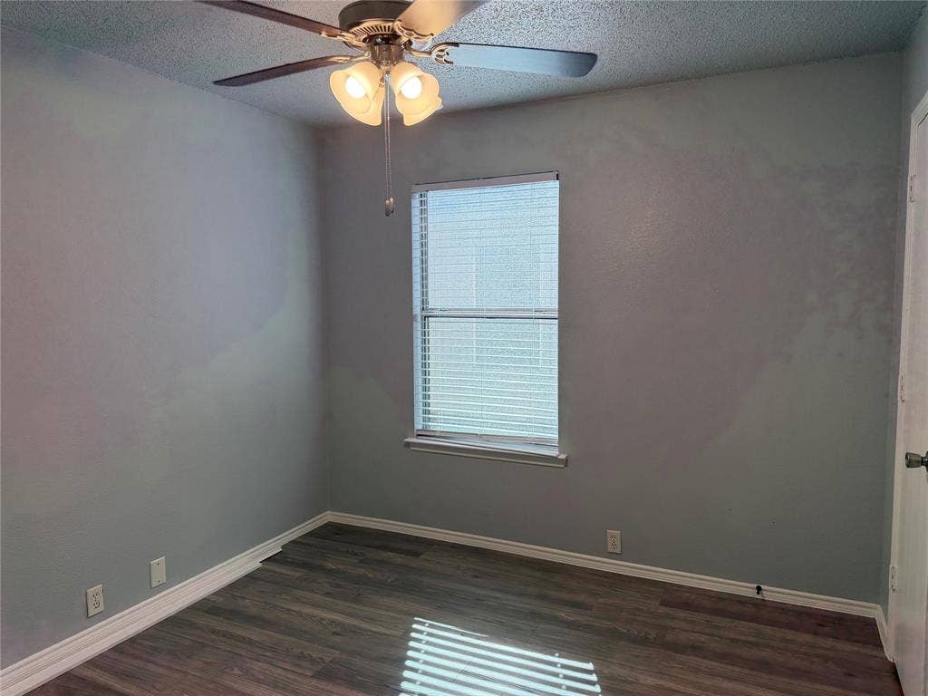 Wood-finish flooring with white trim and a window with blinds