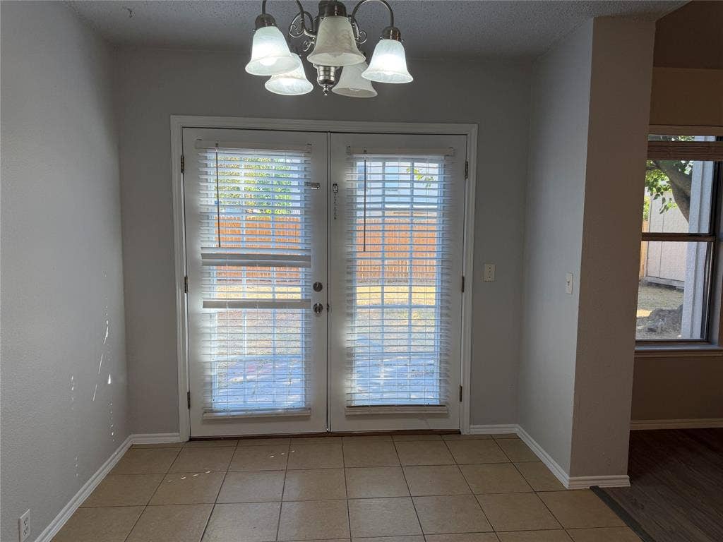 Double French doors with integrated blinds, ceramic tile flooring, and a multi-light chandelier