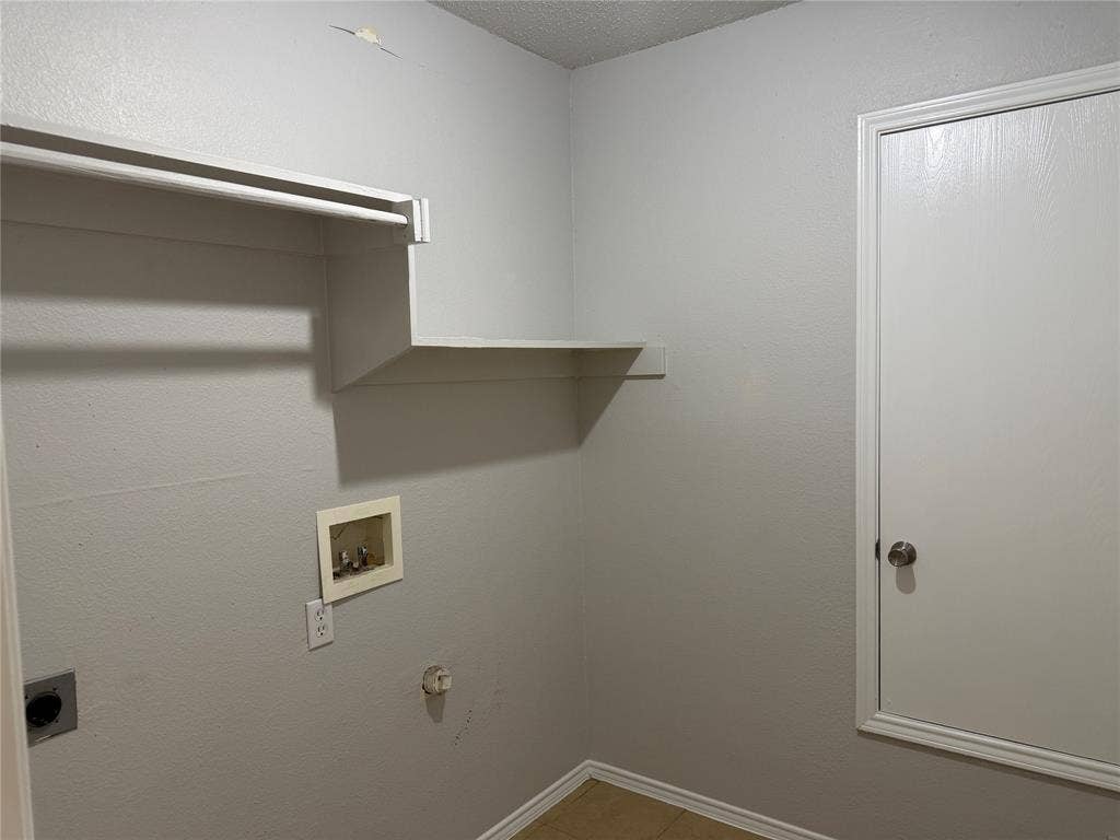 Laundry area featuring built-in shelving, a clothes hanging rod, tile flooring, and utility hookups