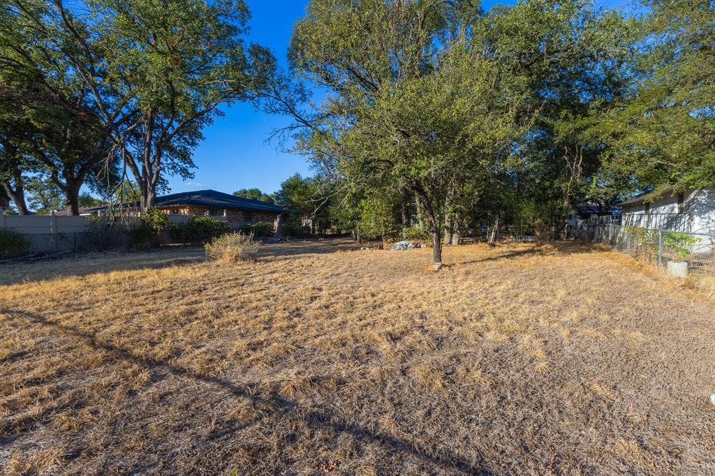 1122 Timberline Street, Bellmead, TX 76705 Expansive outdoor area with mature trees and a chain link fence