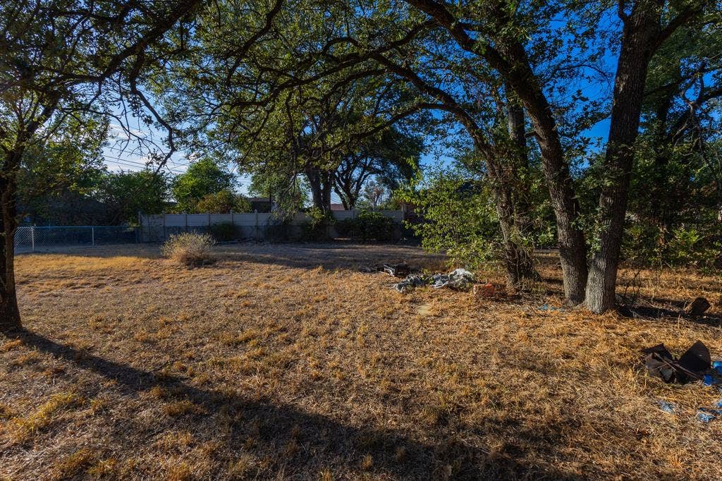 1122 Timberline Street, Bellmead, TX 76705 Expansive lot featuring mature trees and a chain-link perimeter fence
