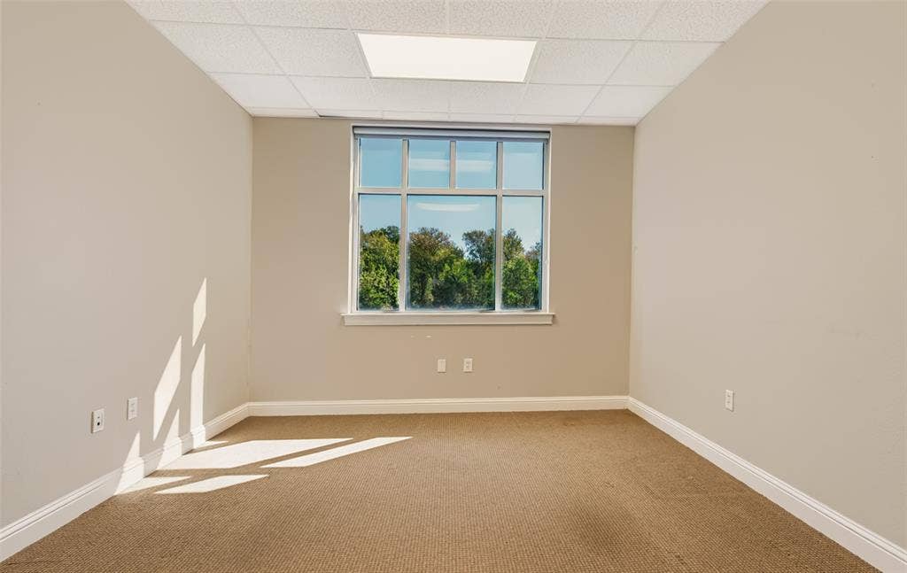 3900 S Stonebridge Drive, #203, McKinney, TX 75070 Neutral wall paint, carpet flooring, a large window with multiple panes, and a drop ceiling with recessed lighting