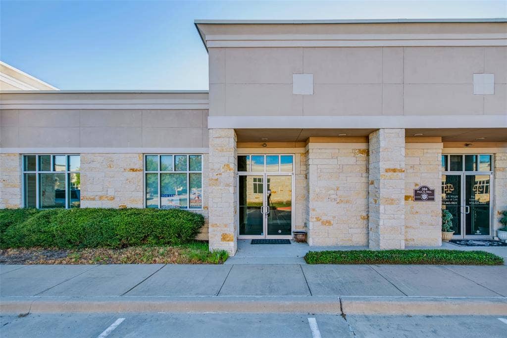 3900 S Stonebridge Drive, #203, McKinney, TX 75070 Stone veneer facade with multiple window units, a clear glass entry door, and a concrete walkway