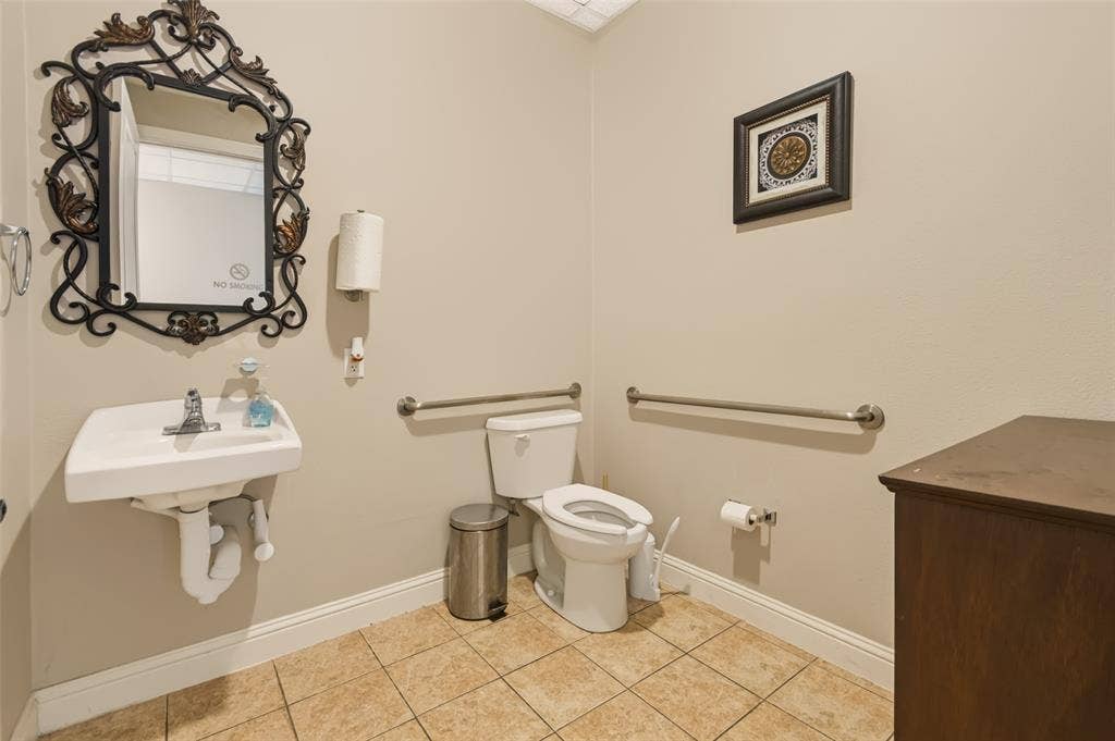 3900 S Stonebridge Drive, #203, McKinney, TX 75070 Wall-mounted sink with chrome faucet, ceramic tile flooring, and two stainless steel grab bars