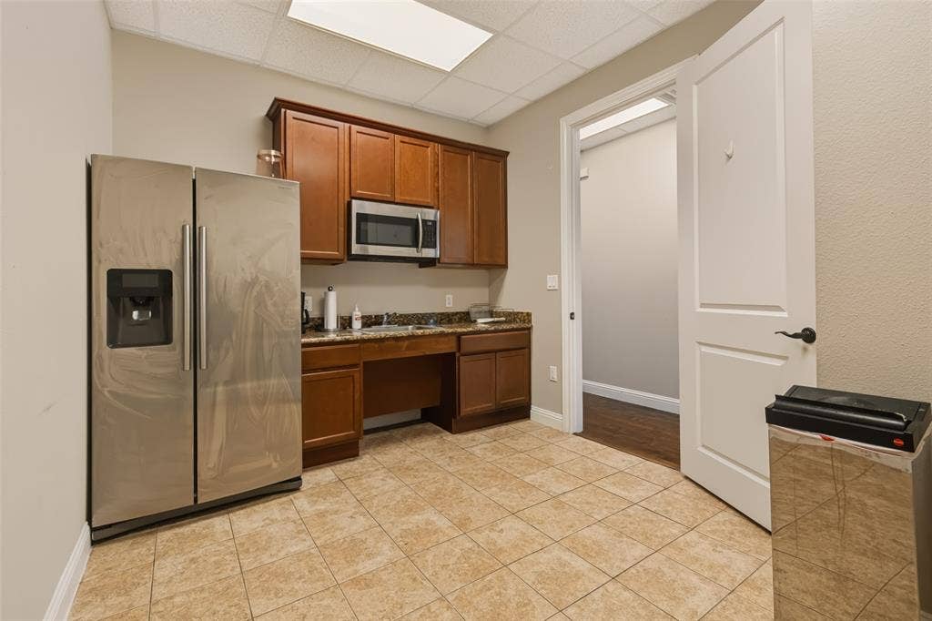 3900 S Stonebridge Drive, #203, McKinney, TX 75070 Built-in cabinetry with a microwave, stainless steel refrigerator, and tiled flooring