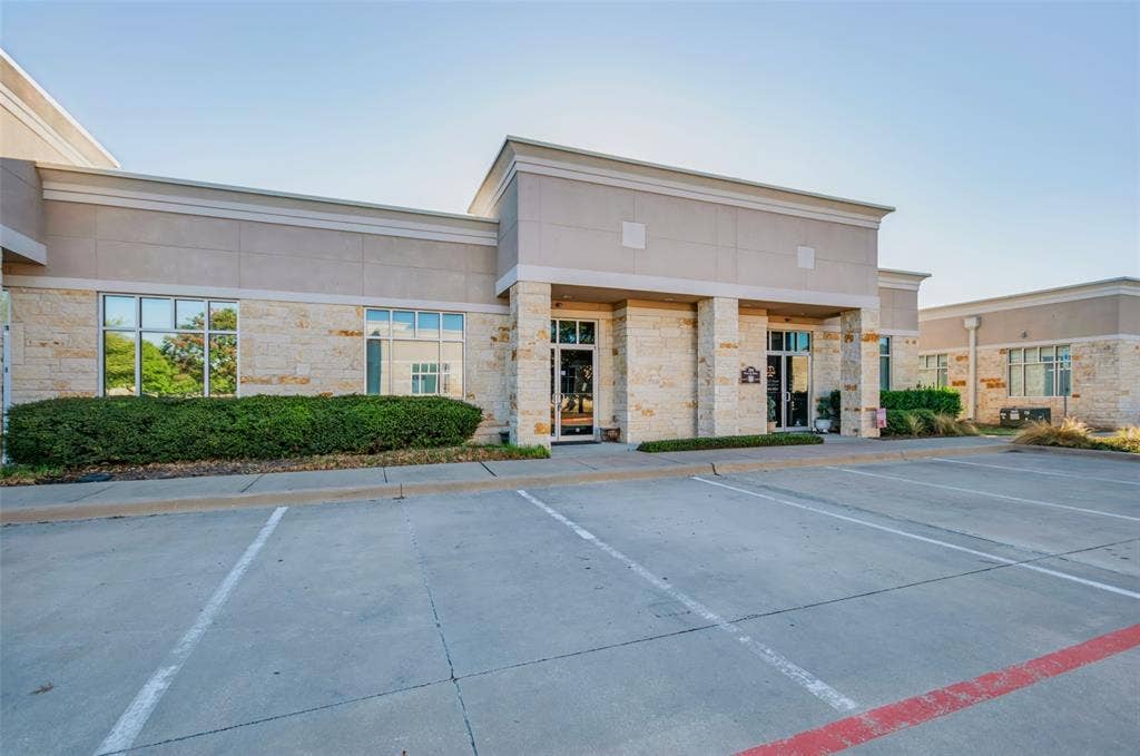 3900 S Stonebridge Drive, #203, McKinney, TX 75070 Stone and stucco exterior with multiple large windows, a prominent covered entrance, and a dedicated paved parking area