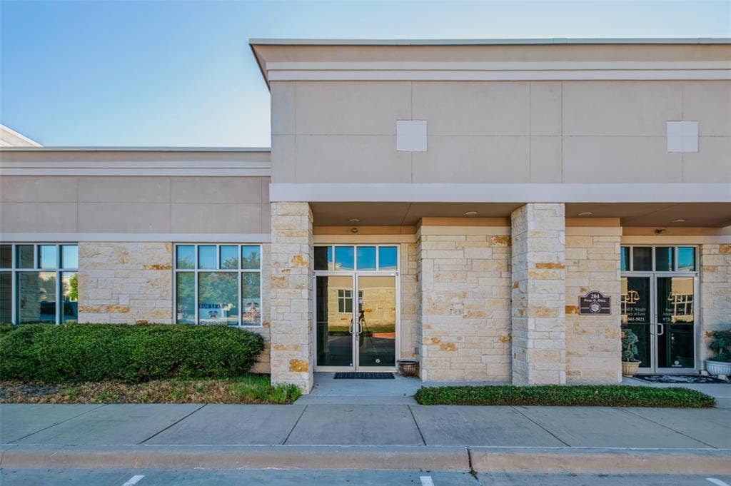 3900 S Stonebridge Drive, #203, McKinney, TX 75070 Stone facade with a neutral stucco finish, large commercial windows, and double glass entry doors