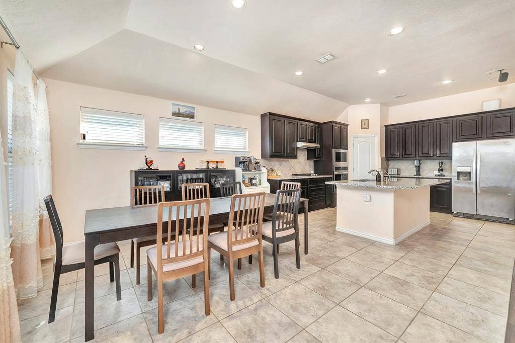 Open kitchen featuring dark cabinetry, stone-finish countertops, stainless steel appliances, a central island, and recessed lighting throughout