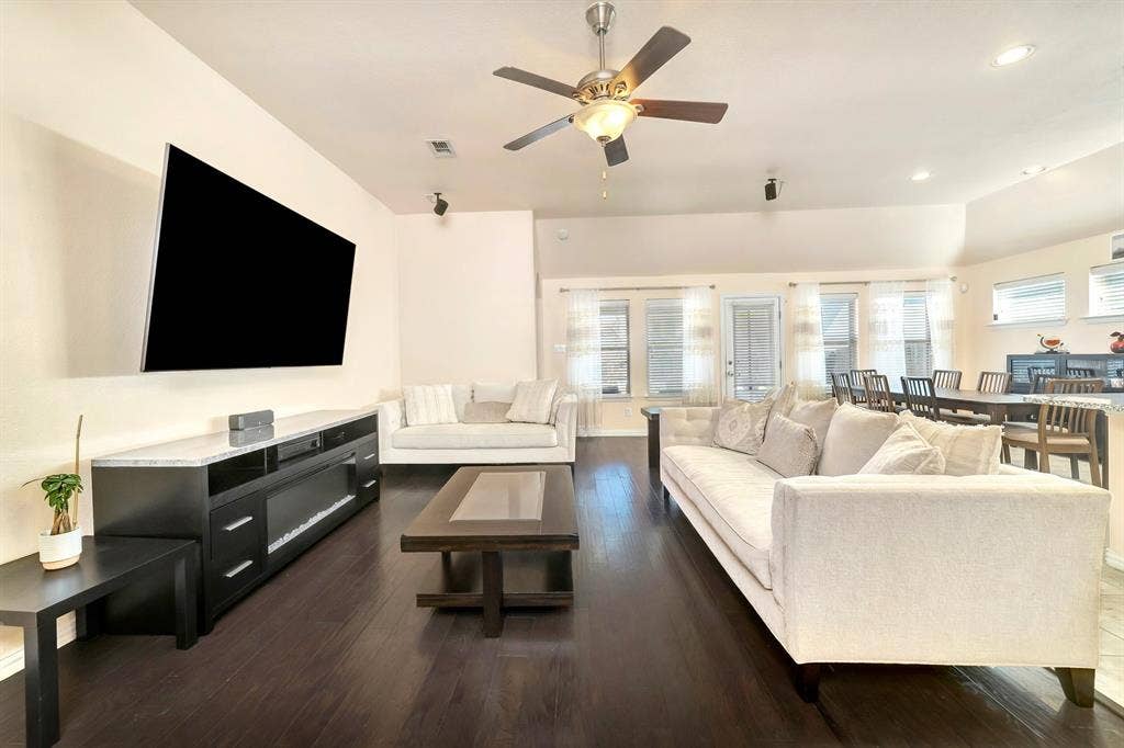 Vaulted ceilings featuring a central ceiling fan, dark wood-finish flooring, and multiple windows providing natural light
