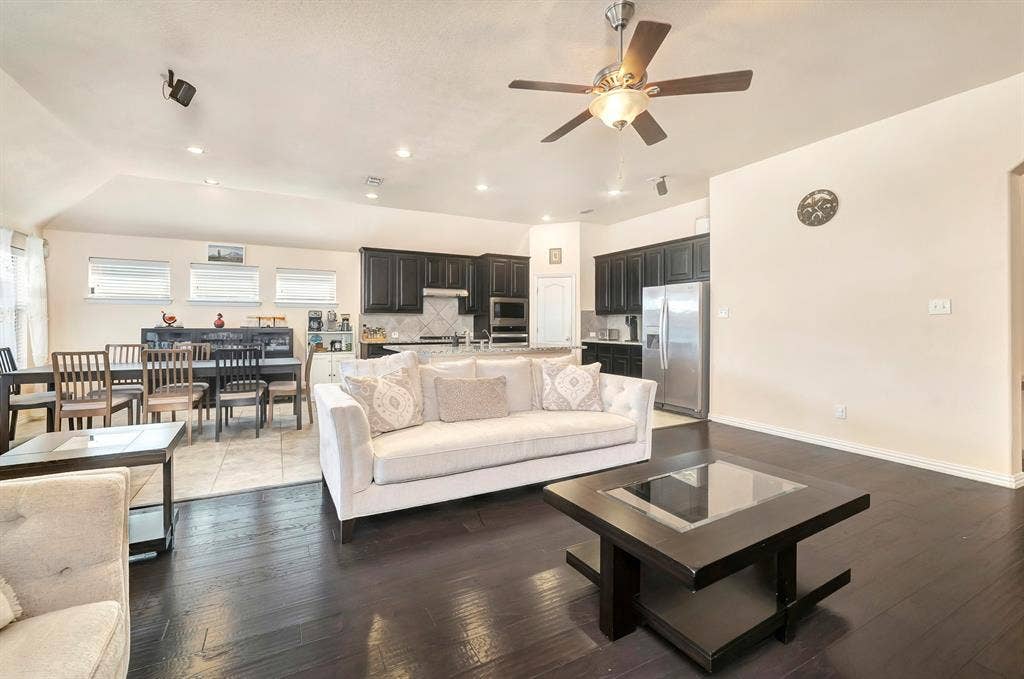 Open-concept interior featuring dark wood-finish flooring, recessed lighting, ceiling fan, and kitchen with dark-finish cabinetry and stainless-steel appliances