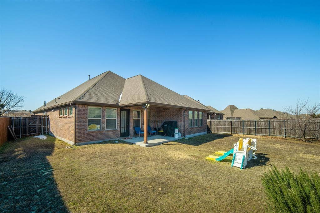 Brick exterior featuring a covered rear patio, hip roofline, and wood privacy fencing