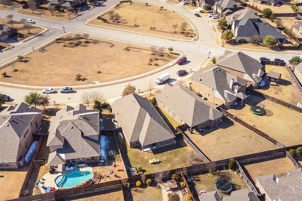 Aerial perspective of a residential corner lot featuring a private in-ground swimming pool, masonry exterior construction, and wood fencing
