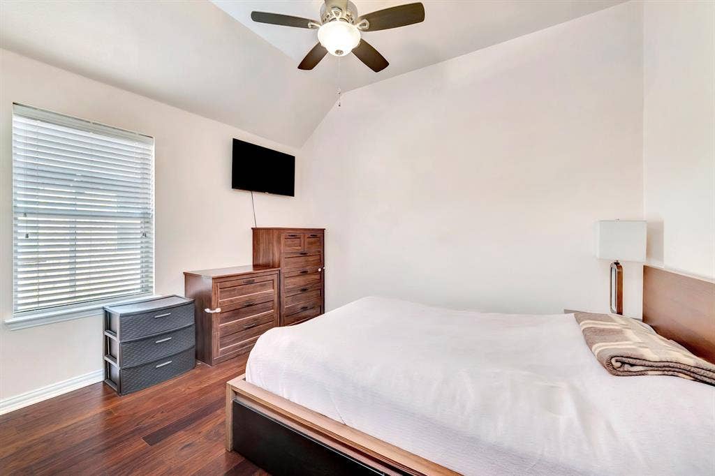 Vaulted ceilings, wood-finish flooring, ceiling fan with integrated lighting, and horizontal window blinds