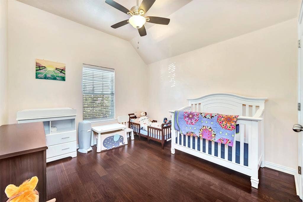 Room featuring vaulted ceilings, dark wood-finish flooring, and a ceiling fan with integrated lighting