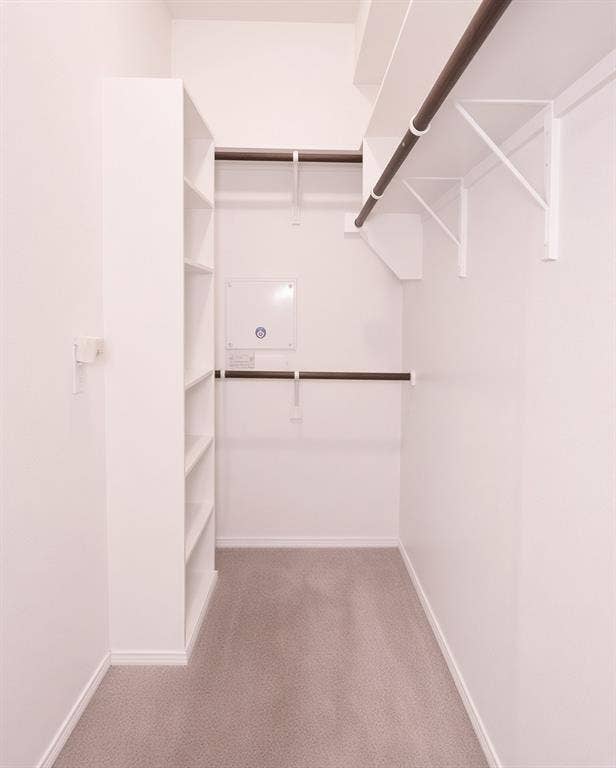 11398 Seguin Drive, Frisco, TX 75035 Walk-in closet featuring white built-in shelving, multiple hanging rods, and light gray carpeting