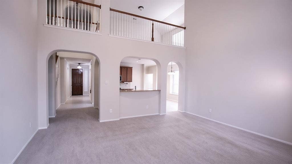 11398 Seguin Drive, Frisco, TX 75035 Two-story living area with arched entryways, an open second-story landing, and carpet flooring