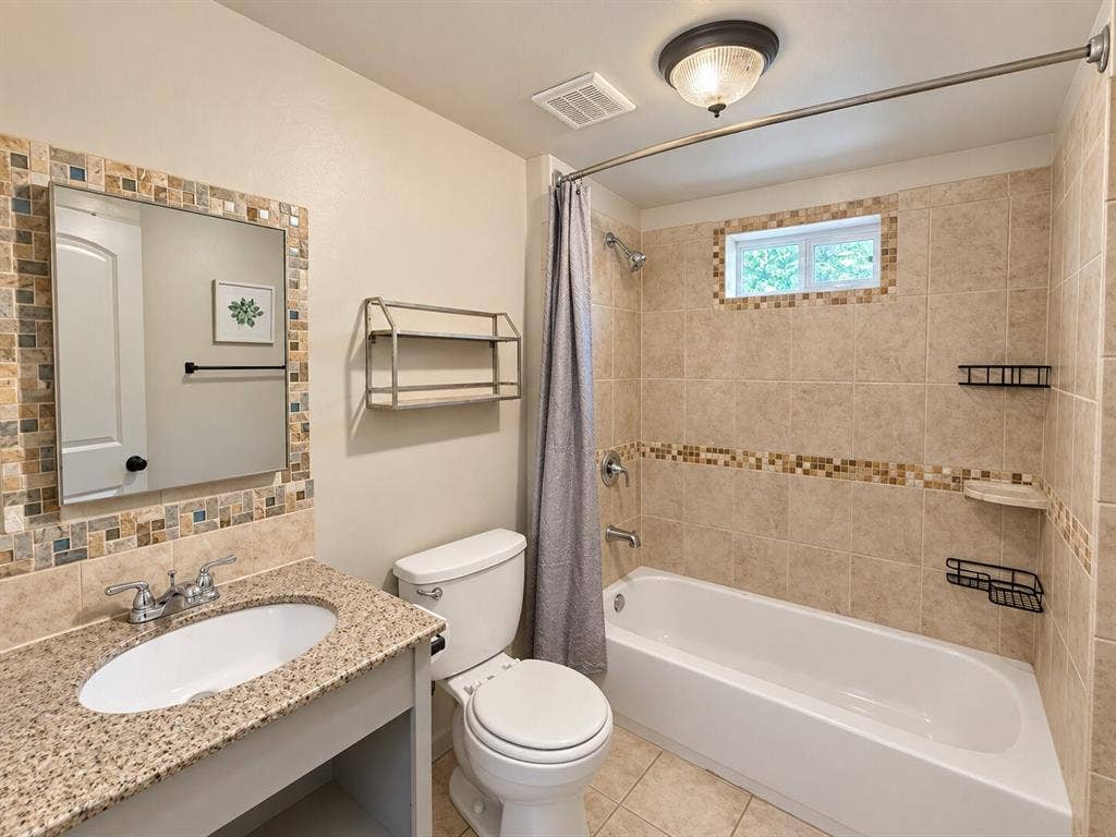 Vanity with stone countertop and integrated sink, chrome faucet, and tiled backsplash